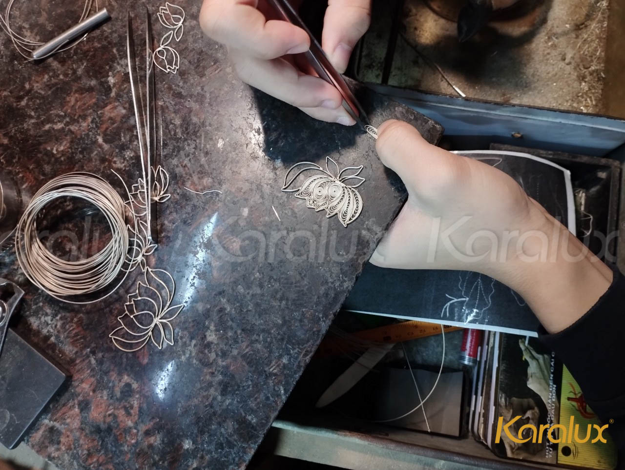Nghệ nhân kim hoàn Karalux đang uốn và hàn các sợi bạc thành hoa sen. Sau khi hoàn thiện, các chi tiết bạc sẽ được mạ vàng và gắn lên tranh.